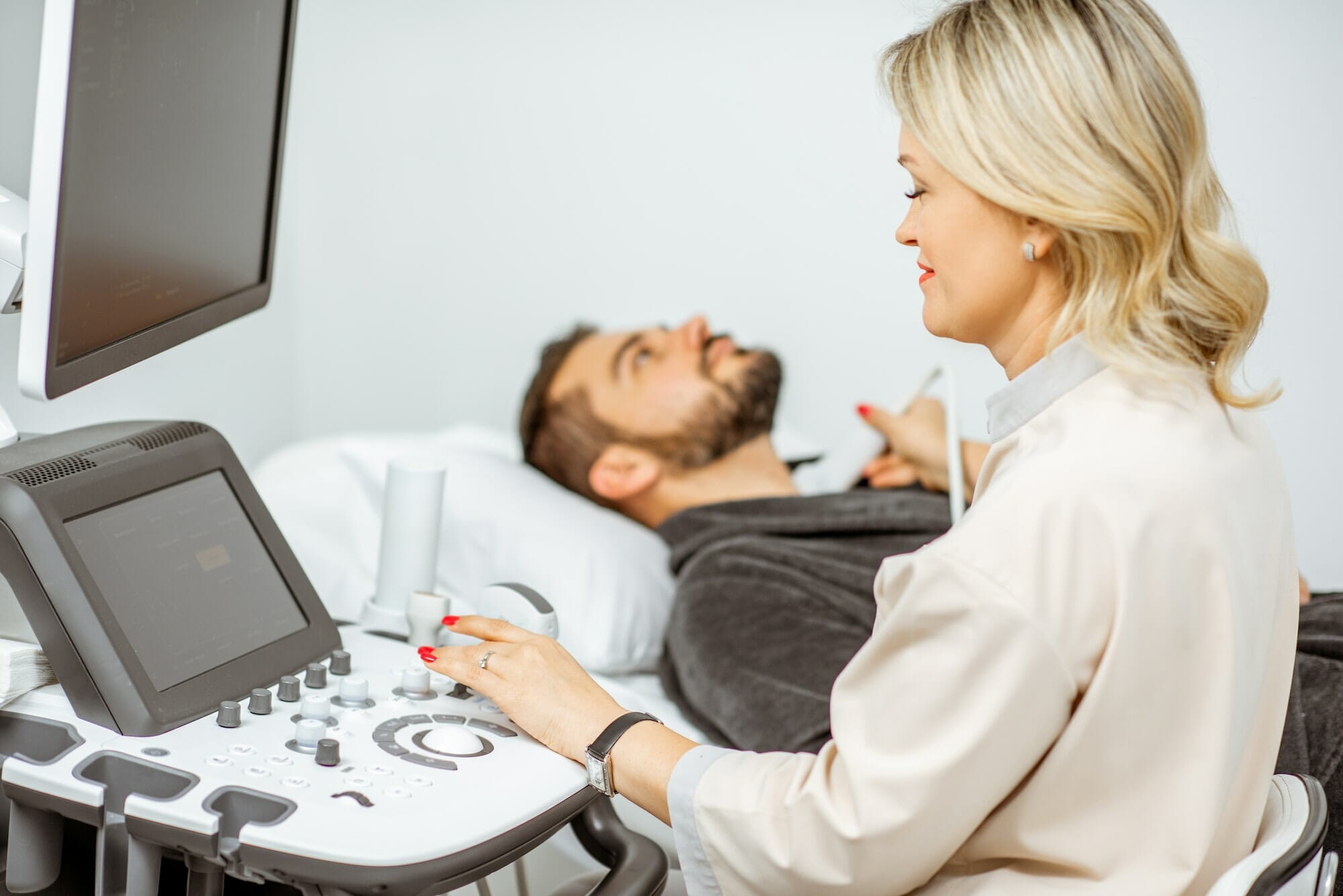 Doctor examining men's thyroid with ultrasound